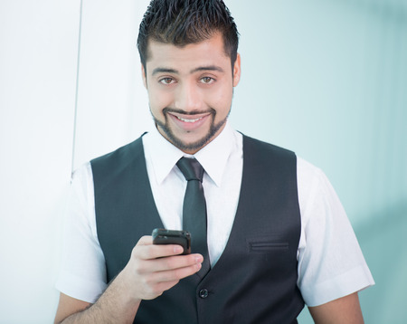 Young Asian Indian businessman standing on office background and talking on the phoneの写真素材