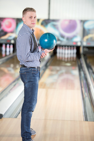 Cheerful young man playing bowlingの写真素材