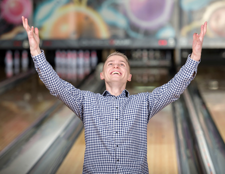 Cheerful young man playing bowlingの写真素材