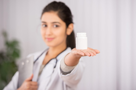 Indian doctor wearing a white coat with pillsの写真素材