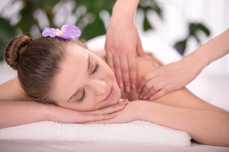Cheerful young woman lying on front receiving messageの写真素材