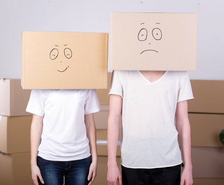 Young happy couple with cardboard boxes on their heads happy his new homeの写真素材