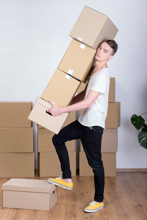 Cheerful man carrying boxes because he is moving in a new houseの写真素材