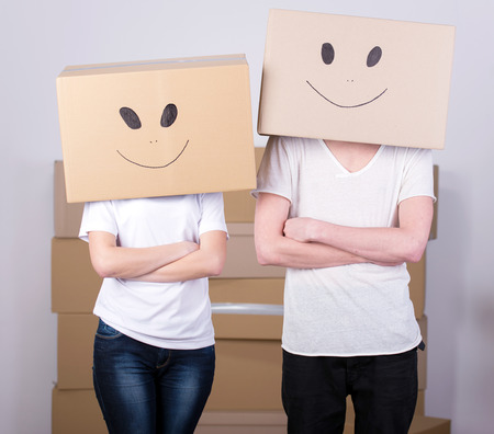 Young happy couple with cardboard boxes on their heads happy his new homeの写真素材
