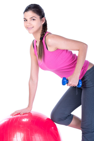 Young sport woman sitting on fitness ball with dumbells. Isolated on white .の写真素材
