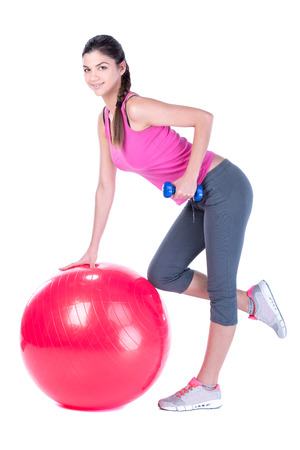Young sport woman sitting on fitness ball with dumbells. Isolated on white .の写真素材