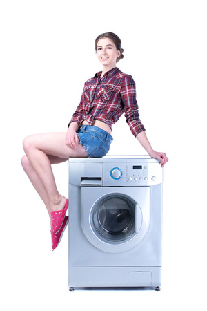 Woman sitting on the washing machine. Isolated on white の写真素材