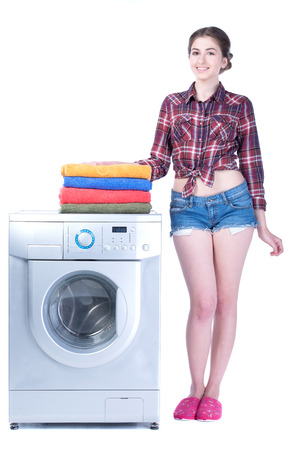 Young beautiful woman doing laundry in the washing machine. Isolated on white の写真素材