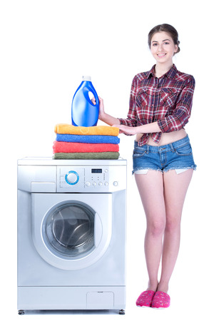 Young beautiful woman doing laundry in the washing machine. Isolated on white の写真素材