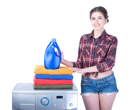 Young beautiful woman doing laundry in the washing machine. Isolated on white の写真素材