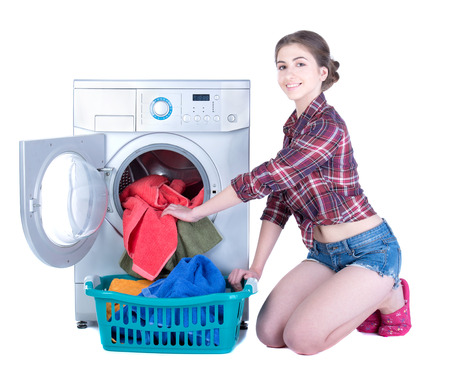 Young beautiful woman doing laundry in the washing machine. Isolated on white の写真素材