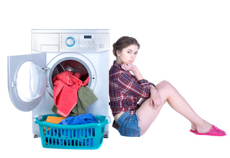 Young beautiful woman doing laundry in the washing machine. Isolated on white backgroundの写真素材