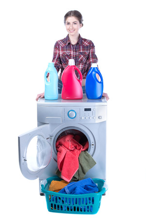 Young beautiful woman doing laundry in the washing machine. Isolated on white の写真素材