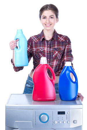 Young beautiful woman doing laundry in the washing machine. Isolated on white の写真素材