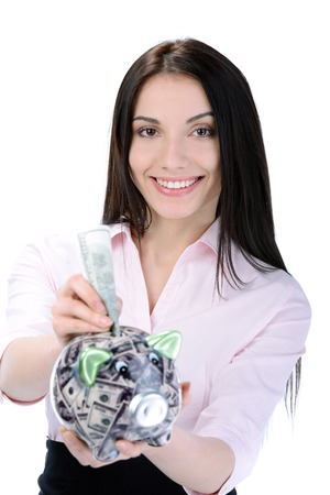 Business woman saving money in a piggybank - isolated over a white backgroundの写真素材