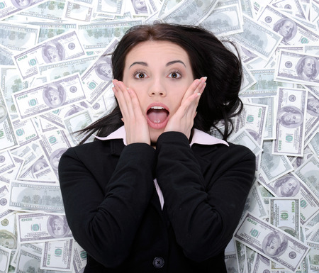 Young business woman resting upon money on a white backgroundの写真素材