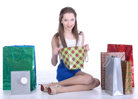 Portrait of young woman carrying shopping bags against white backgroundの写真素材