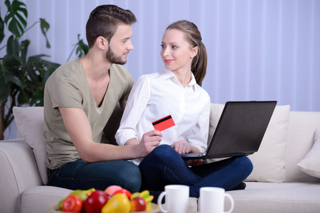 Portrait of happy couple shopping online with credit card in houseの写真素材