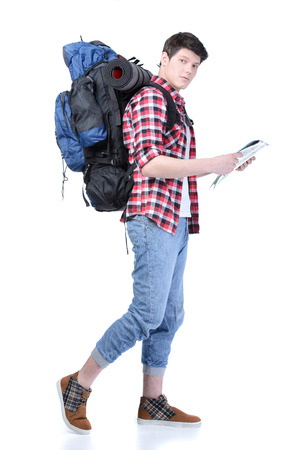 Young man with backpack and a map walking isolated on white backgroundの写真素材