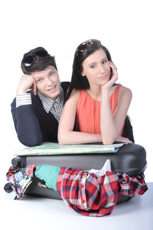 Couple packs up suitcase with clothing for travel, isolated on white. Concept of romantic vacations and lovely honeymoonの写真素材