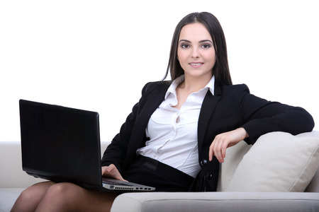 Business woman working on a laptop sitting on sofaの写真素材