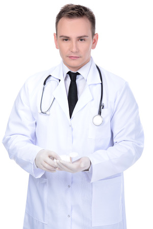 Closeup of a male pharmacist holding out tablets isolated on whiteの写真素材
