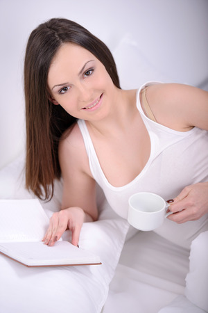 leisure reading woman is comfortable lying on her bed with a bookの写真素材