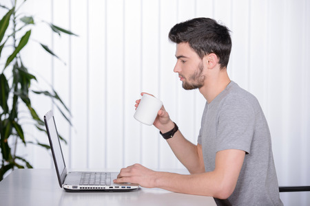 Work at home. Beautiful young beard man working at his workplaceの写真素材