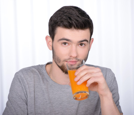 Good looking man drinking orange juice in his homeの写真素材