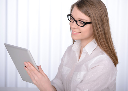 Working in an office. Young pretty business woman with notebook in the officeの写真素材