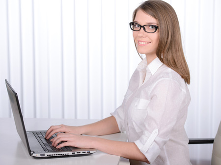 Working in an office. Young pretty business woman with notebook in the officeの写真素材