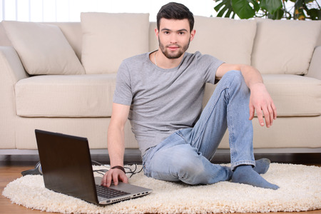 Work at home. Beautiful young beard man working at his workplaceの写真素材