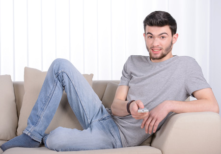 Man changes channels TV remote control in the living room at homeの写真素材