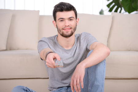 Man changes channels TV remote control in the living room at homeの写真素材