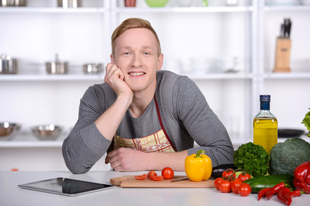 Handsome man cooking at home preparing salad in kitchen.の写真素材