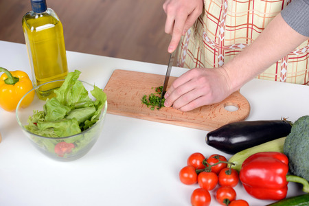 Handsome man cooking at home preparing salad in kitchen.の写真素材
