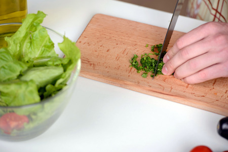 Handsome man cooking at home preparing salad in kitchen.の写真素材
