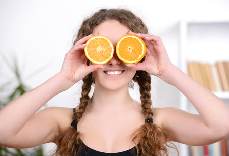Cheerful young beautiful woman with orange, at fitness center or gymの写真素材