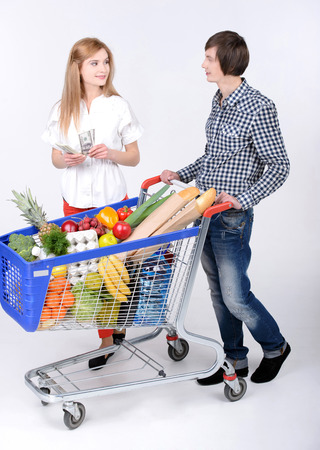 Supermarket. Happy couple with a shopping cart. Isolated over white background.の写真素材