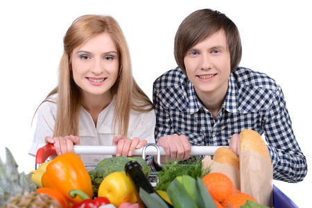 Supermarket. Happy couple with a shopping cart. Isolated over white background.の写真素材