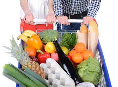 Supermarket. Happy couple with a shopping cart. Isolated over white background.の写真素材
