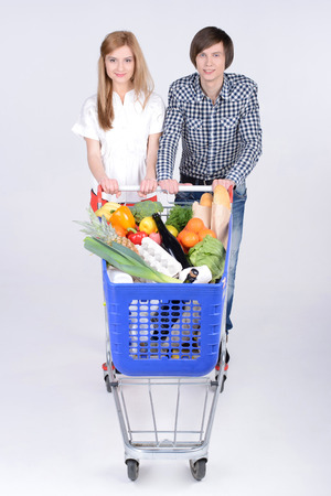 Supermarket. Happy couple with a shopping cart. Isolated over white background.の写真素材
