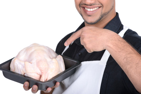 Young handsome man holding chicken. professional butcher in apron smiling and cooking chickenの写真素材