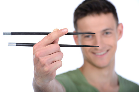 Man eating sushi. Cheerful young man eating sushi while standing isolated on whiteの写真素材