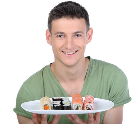 Man eating sushi. Cheerful young man eating sushi while standing isolated on whiteの写真素材