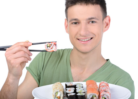 Man eating sushi. Cheerful young man eating sushi while standing isolated on whiteの写真素材