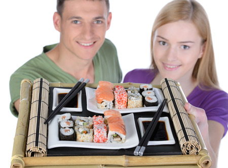 Eating sushi together. Beautiful couple eating sushi while sitting close to each otherの写真素材