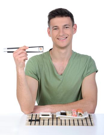 Man eating sushi. Cheerful young man eating sushi while standing isolated on whiteの写真素材