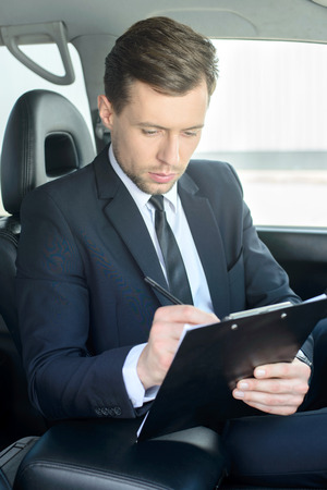 Young successful businessman riding in the carの写真素材