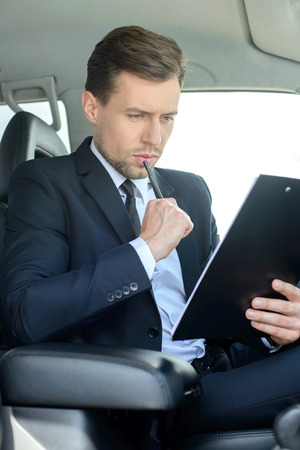 Young successful businessman riding in the carの写真素材